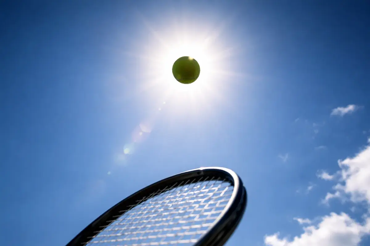 Tennista che lancia la pallina in aria per servire su un campo in cemento